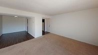 Located at 320 S Drake Rd in Kalamazoo, Michigan, this single-floor unit offers a well-organized layout designed for comfortable everyday living. The living area is finished with neutral-toned carpet and features a large window dressed with vertical blinds, allowing abundant natural light to fill the space and providing views of the surrounding greenery outside.

The kitchen is a standout feature, equipped with dark espresso-toned cabinetry that contrasts cleanly against light countertops and white appliances, including a refrigerator, electric range, and dishwasher. Rich wood-look flooring runs throughout the kitchen and adjacent areas, adding warmth and durability. Track lighting above the kitchen adds both function and a modern touch.

The bedrooms continue the neutral, carpeted aesthetic, each featuring windows with vertical blinds that bring in natural light and outdoor views of the tree-lined surroundings. The rooms offer a clean, open canvas well-suited for a variety of furniture arrangements.

The bathroom is finished in a crisp, all-white palette with mosaic tile flooring, a full-size soaking tub with shower, a vanity with mirror, and classic tile wall accents. The overall design of the unit is clean, practical, and move-in ready, making it a solid choice for those seeking a functional home in the Kalamazoo area.