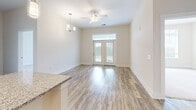 Located in Knightdale, NC, this well-appointed 2-bedroom, 2-bathroom residence offers a thoughtfully designed single-level layout. The kitchen serves as a central highlight, featuring gray shaker-style cabinetry, granite countertops, stainless steel appliances, and a large central island with pendant lighting overhead — ideal for both cooking and casual dining. Wood-style luxury vinyl plank flooring flows throughout the main living areas, adding warmth and continuity.

The living area benefits from abundant natural light, with French doors topped by a transom window and a ceiling fan with chandelier accent lighting. Both bedrooms are carpeted and generously sized, with large windows that invite natural light and outdoor views. The spacious primary bedroom includes a walk-in closet outfitted with wire shelving for organized storage, and a second closet provides additional convenience.

The primary bathroom is elegantly finished with granite countertops, gray cabinetry with gold hardware, a walk-in glass-enclosed shower, and wood-style flooring. The second bathroom is equally well-appointed. Each closet features wire rack shelving systems for practical organization. The overall aesthetic is clean and modern, with a neutral palette throughout that creates a bright, airy atmosphere.