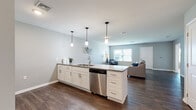 Located at 2410 Oakwood Hills Dr in Mechanicsburg, PA, this well-appointed single-floor residence offers a thoughtful layout with 1 bedroom, 2 bathrooms, a dedicated office, and a generous open-concept living area. The kitchen is a standout feature, showcasing a large center island with granite countertops, white shaker cabinetry, stainless steel appliances including a refrigerator, gas range, microwave, and dishwasher, all illuminated by stylish pendant lighting. Rich hardwood-style flooring flows seamlessly from the kitchen through the open living room, which is bathed in natural light from large windows. The spacious bedroom features plush carpeting, a walk-in closet, and windows overlooking the outdoors, providing a calm and comfortable retreat. Both bathrooms are finished with granite-topped white vanities and wood-style flooring; one includes a full tub-shower combination. The flexible office space features neutral carpet and soft gray walls, ideal for work or study. Throughout the residence, a consistent cool-gray color palette, clean white trim, and modern fixtures create a cohesive, contemporary aesthetic that is both functional and inviting.
