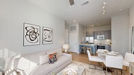 Located in Orlando, FL, this thoughtfully designed one-bedroom, one-bathroom residence offers a bright, open-concept layout with modern finishes throughout. Light gray walls, light-toned wood flooring, and high ceilings create an airy, cohesive atmosphere from room to room.

The living area features large windows that flood the space with natural light and provides ample room for both a seating arrangement and a dining set. Track lighting and a ceiling fan add both function and style. The kitchen is well-appointed with gray shaker cabinets, a white subway tile backsplash, stainless steel appliances including a side-by-side refrigerator and range, and a kitchen island with bar seating and a built-in wine rack — ideal for casual dining and entertaining.

The bedroom is a serene retreat, benefiting from large windows with outdoor views, soft neutral tones, and elevated ceiling height. A dedicated walk-in closet with wire shelving provides organized storage. The full bathroom features a blue vanity with quartz countertop, a tub-shower combo with white subway tile surround, and wood-look flooring for a clean, contemporary feel.

A dedicated laundry room with a stacked washer and dryer and additional wire shelving rounds out the practical amenities of this well-planned residence.