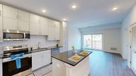 Located at 37 North York Road in Hatboro, PA, this thoughtfully designed one-bedroom, two-bathroom residence offers a clean, modern aesthetic throughout its efficiently laid-out single floor. The open-concept living and kitchen area serves as the heart of the home, showcasing light hardwood flooring, recessed lighting, and a bright, airy atmosphere. The kitchen is well-appointed with white shaker-style cabinetry extending to the ceiling for ample storage, dark granite countertops, a classic subway tile backsplash, and a full suite of stainless steel appliances including a range, microwave, dishwasher, and refrigerator. A central island with matching granite provides additional prep and dining space. The spacious bedroom features two windows that allow natural light to fill the room, offering views of the surrounding greenery. A barn-style sliding door adds a modern touch and leads to a dedicated closet. Both bathrooms are finished with neutral tile flooring, white vanities with granite countertops, and clean white walls, maintaining the home's cohesive, contemporary style. A private balcony overlooks a well-maintained parking area with landscaped surroundings. The unit includes convenient on-site parking.