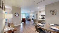 Located at 104 Turnpike Rd in Chelmsford, MA, this thoughtfully designed 2-bedroom, 2-bathroom residence offers a comfortable and modern living experience on a single floor. The open-concept layout seamlessly connects the kitchen, dining area, and living room, creating a bright and cohesive space ideal for both everyday living and entertaining. Wide-plank hardwood-style flooring flows throughout the main living areas, adding warmth and continuity.

The kitchen is a standout feature, boasting white shaker cabinetry, granite countertops, a center island with bar seating, and a full suite of stainless steel appliances including a range, microwave, and refrigerator. Track lighting and recessed fixtures illuminate the space effectively. The adjacent living room is generously proportioned, with large sliding glass doors that invite natural light and provide outdoor access.

The spacious primary bedroom features plush carpeting, a large window, and ample room for a full furniture arrangement. The second bedroom is equally comfortable, also finished with carpet and a bright window. Both bathrooms are clean and modern, featuring white vanities with granite countertops, large mirrors, and hardwood-style flooring. This residence offers a polished, move-in-ready environment with a neutral palette throughout.