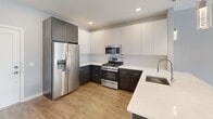 This thoughtfully designed one-bedroom, one-bathroom residence at 202 Park Blvd in Cherry Hill, NJ offers a clean, modern aesthetic throughout its well-proportioned floor plan. The open-concept living and kitchen area serves as the heart of the home, where warm wood-look flooring flows seamlessly from the spacious living room to the kitchen. Large windows allow generous natural light to fill the living space, creating an inviting, airy atmosphere.

The kitchen is a standout feature, showcasing a two-tone design with dark espresso lower cabinets and crisp white upper cabinetry, accented by a classic subway tile backsplash and bright white quartz countertops. A full suite of stainless steel appliances — including a gas range, built-in microwave, dishwasher, and French door refrigerator — complete the space, while elegant pendant lighting adds a refined touch.

The bedroom is a well-sized retreat with a large window overlooking the outdoors, providing natural light and views. Two closets offer excellent storage. The bathroom features large-format floor tiles, a dark-wood vanity with a white countertop, a mirrored medicine cabinet, and a full tiled tub-shower surround. Additional conveniences include a dedicated laundry area and a private balcony, rounding out this functional and stylish residence.