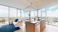 Located at 50 Clinton Pl in New Rochelle, NY, this thoughtfully designed 3-bedroom, 1-bathroom residence combines modern architecture with sweeping panoramic views. The open-concept kitchen and living area is the heart of the home, anchored by dramatic floor-to-ceiling windows that frame breathtaking views of the water and surrounding cityscape, flooding the space with natural light. The kitchen features a sleek center island with dark countertops, warm wood cabinetry, stainless steel appliances, and pendant lighting, flowing seamlessly into the living area with light hardwood flooring throughout. The living room offers generous space for entertaining, with expansive glazing that showcases elevated views of New Rochelle's skyline and beyond. The primary bedroom benefits from the same floor-to-ceiling window treatment, offering serene outdoor views and a bright, airy atmosphere. Two additional bedrooms are finished in a clean, neutral palette with hardwood floors and ample natural light. The bathroom is elegantly appointed with large-format stone tile flooring, warm wood vanity cabinetry, a backlit mirror, and half-wall grey tile detailing. A dedicated walk-in closet with built-in shelving and hanging rails adds practical storage. A hallway connects all rooms with ease, completing this well-appointed, light-filled residence.