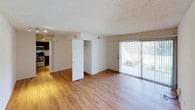 This 2-bedroom unit is laid out across a single floor, offering a functional and comfortable living environment. The open living area features warm hardwood-style flooring and a sliding glass door fitted with vertical blinds that allows abundant natural light to flood the space while providing direct access to an outdoor patio. A built-in closet is conveniently located near the entrance, adding practical storage to the main living area.

The kitchen is outfitted with rich, dark wood cabinetry, marble-look countertops, and stainless steel appliances including an electric range, over-the-range microwave, and a deep double-basin sink — offering both style and functionality for everyday cooking.

The primary bedroom is generously sized, featuring plush carpeting, a textured ceiling, and a large bifold closet with built-in shelving for organized storage. It also provides access to a full bathroom complete with marble-look countertops, hardwood-style flooring, and a tiled shower-tub combination.

The second bedroom also features hardwood-style flooring and a textured ceiling, with bright white walls that create a clean, neutral canvas. Both bedrooms are well-lit by natural light from windows overlooking the exterior. Throughout the unit, the consistent use of updated finishes and neutral tones creates a cohesive and move-in-ready atmosphere.