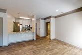This single-floor residence offers a well-designed open layout that seamlessly connects the main living areas. The spacious living room is finished with durable wood-look flooring, crown molding, and a ceiling fan with light fixture. A large arched window floods the space with natural light while framing views of surrounding greenery, complemented by an additional side window fitted with blinds.

The kitchen is thoughtfully appointed with white shaker-style cabinetry, granite-look countertops, a subway tile backsplash, and a full suite of stainless steel appliances including a refrigerator, electric range, and over-the-range microwave. A peninsula with pendant lighting defines the boundary between the kitchen and living areas, adding both function and style.

The bedrooms are carpeted for comfort and each include ceiling fans and windows overlooking lush outdoor views. The bathroom features wood-look tile flooring, a granite-top vanity with white cabinetry, a large mirror, and modern lighting fixtures.

A dedicated laundry area houses a full-size washer with overhead shelving and an electrical panel. Neutral tones throughout create a cohesive and inviting atmosphere well-suited for everyday living.