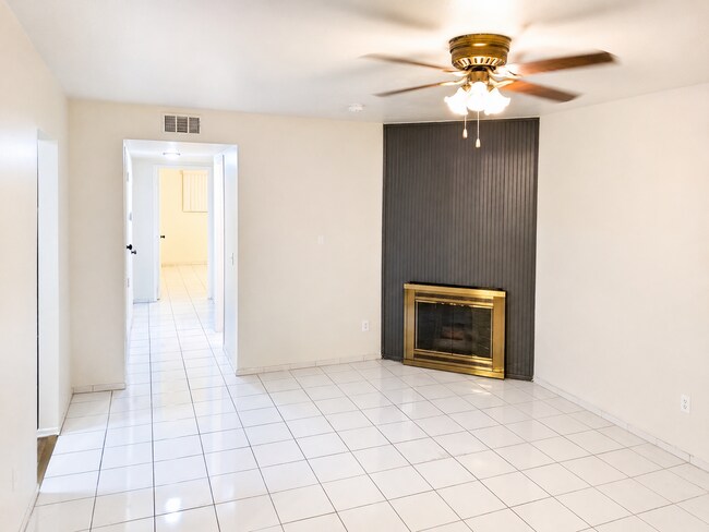 Amplia sala de estar con chimenea decorativa, paredes neutras, suelo de baldosas y una cómoda cama. - 339 E Taft Ave