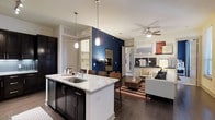 This 2-bedroom, 2-bathroom residence is designed with an open-concept floor plan that maximizes flow and functionality across a single level. The kitchen serves as the heart of the home, featuring a central island with a striking marble-style countertop, an undermount sink, and pendant lighting that adds a polished touch. Dark cabinetry provides bold contrast against the light countertops, while stainless steel appliances complete the modern aesthetic. Bar seating at the island creates a natural transition into the dining area, making the space ideal for both everyday living and entertaining. A dramatic navy blue accent wall anchors the open living and dining zone, adding depth and visual interest. The living area is finished with wood-style flooring, a ceiling fan for year-round comfort, and ample space for seating arrangements. Neutral walls throughout allow the design accents to stand out, while recessed lighting ensures the space is well-lit. The layout offers a comfortable and cohesive living environment, with two bedrooms and two full bathrooms providing privacy and convenience. Clean lines, contemporary finishes, and a thoughtful design make this residence a functional and stylish place to call home.