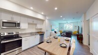 Located at 2640 Wagon Wheel Rd in Oxnard, California, this single-story residence offers a thoughtfully designed open-concept layout with modern finishes throughout. The living area is bright and welcoming, featuring wood-style flooring, a ceiling fan, and a glass door that fills the space with natural light. The seamless flow into the kitchen makes this area ideal for both everyday living and entertaining.

The kitchen is well-appointed with medium-toned shaker-style cabinetry, white quartz countertops, stainless steel appliances including a refrigerator, range, microwave, and dishwasher, and a central island that doubles as additional prep and dining space. Wood-style flooring continues throughout, maintaining a cohesive aesthetic.

Two bedrooms provide comfortable retreats, each featuring plush carpeting, large windows with outdoor views, and ample natural light. The two bathrooms are finished with wood-style flooring, white quartz vanity countertops, matching cabinetry, and tub-shower combinations with white tile surrounds. The overall ambiance of this residence is clean, contemporary, and inviting, with a neutral palette that complements the Southern California setting.