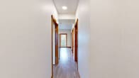 Located at 1200 Billy Frank Jr St in Bellingham, WA, this single-floor, 4-bedroom, 1-bathroom unit offers a thoughtfully organized layout designed to maximize functionality. Light hardwood-style flooring and warm wood-toned baseboards run consistently throughout, creating a cohesive and clean aesthetic.

The kitchen is well-appointed with light maple cabinetry, stainless steel appliances including a refrigerator, range, microwave, and dishwasher, recessed lighting, and ample counter space. An adjacent dining area benefits from natural light through a window and direct access to a private balcony overlooking greenery.

Each of the four bedrooms features light-toned flooring, white walls, and individual closets with hanging rods for storage. The primary bedroom includes a window with views of the surrounding area and a wall-mounted HVAC unit. Several bedrooms share a similar open-closet design, offering practical storage solutions.

The shared bathroom is clean and functional, featuring a full tub/shower combination, a toilet, a wide vanity with wood cabinetry, and a white countertop. A hallway connects all rooms, contributing to the efficient single-floor flow. The unit's bright, neutral palette and consistent finishes give it a modern, move-in-ready feel throughout.