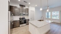 Located at 1540 Edgefield Dr in Garland, TX, this one-bedroom, one-bathroom residence offers a thoughtfully designed single-floor layout with modern finishes throughout. Light-toned hardwood-style flooring flows seamlessly across every room, creating a cohesive and clean aesthetic.

The kitchen serves as the heart of the home, anchored by a granite-topped island with an undermount sink and pendant lighting overhead. Dark espresso cabinetry provides ample storage and contrasts elegantly with the light countertops. Stainless steel appliances, including a range with microwave and refrigerator, complete the fully equipped space.

The open layout connects the kitchen to the living area, which benefits from natural light through a large window and is equipped with a ceiling fan. The bedroom is a comfortable, well-proportioned retreat featuring its own ceiling fan, a window with natural light, and dedicated closet space.

The bathroom is finished to a high standard, showcasing dark wood vanity cabinetry with granite countertops, a wide mirror with vanity lighting, and a glass-enclosed walk-in shower with white tile surround. Hardwood-style flooring continues into the bathroom, maintaining a consistent design language throughout the space.

Clean white walls, recessed lighting, and modern hardware complete the contemporary character of this well-maintained Garland residence.
