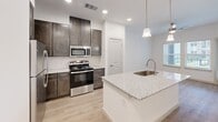 Located at 1540 Edgefield Dr in Garland, TX, this one-bedroom, one-bathroom unit offers a thoughtfully designed layout with modern finishes throughout. Light wood-look flooring runs seamlessly across the entire space, complementing the crisp white walls and creating a bright, cohesive feel.

The kitchen is a standout feature, showcasing dark espresso cabinetry that extends to the ceiling for ample storage, granite countertops, and a central island with a built-in sink and pendant lighting overhead. Stainless steel appliances — including a range, microwave, and refrigerator — complete the polished look. The open sightlines from the kitchen connect naturally to the living and dining areas, making the space feel open and functional.

The bedroom is a comfortable retreat, featuring a ceiling fan with light, natural light from double windows with outdoor views, and clean, neutral walls. A dedicated closet provides organized storage. The bathroom mirrors the kitchen's refined aesthetic with dark wood cabinetry, a granite vanity, a large mirror with overhead lighting, and a glass-enclosed shower. The unit also benefits from ceiling fans in multiple rooms, recessed lighting, and a clean, move-in-ready condition throughout.