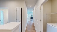 This single-floor home offers a thoughtfully designed layout featuring 2 bedrooms, 4 bathrooms, and 2 closets. The open-concept kitchen and living area serves as the heart of the home, showcasing white upper cabinetry paired with gray lower cabinets, granite countertops, a large center island with pendant lighting, and stainless steel appliances. Light hardwood-style flooring runs throughout the main living areas, contributing to a bright and cohesive aesthetic. A central hallway connects the living spaces to the bedrooms, with clean white panel doors and recessed lighting maintaining a modern, minimalist feel. The primary bedroom is generously sized, featuring soft carpet flooring, and is accompanied by a dedicated closet. The second bedroom also offers carpeted flooring, a ceiling fan, and natural light from a large window with neighborhood views. The bathrooms are finished with white subway tile surrounds in the tub-shower combinations and brushed nickel fixtures. Spacious walk-in closets with wire shelving systems provide practical storage. The overall ambiance of the home is clean, contemporary, and move-in ready, with a neutral color palette and consistent finishes creating a unified and welcoming atmosphere throughout.