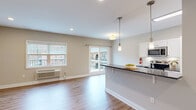 Located at 313 Creek Drive in Saint Davids, PA, this three-bedroom, two-bathroom single-floor residence offers a thoughtfully designed open-concept layout. The combined kitchen and living area serves as the heart of the home, featuring light wood-style flooring, recessed lighting, and a stylish kitchen with white cabinetry, dark granite countertops, stainless steel appliances, and a peninsula with pendant lighting overhead. Sliding glass doors and multiple windows flood the living area with natural light and open to a private balcony overlooking the landscaped brick community courtyard. The primary bedroom is a generously sized retreat with plush carpeting, a ceiling fan, a walk-in closet with built-in shelving, and a private en-suite bathroom. The additional bedrooms also feature carpet flooring, ceiling fans, and windows that bring in natural light. The bathrooms are finished with clean white vanities and framed mirrors, conveying a crisp, modern aesthetic. Throughout the residence, neutral warm-toned walls and clean white trim create a cohesive and inviting atmosphere. The exterior brick building with manicured grounds and tree-lined surroundings adds classic charm to this well-appointed Saint Davids address.