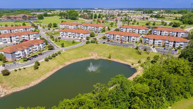 Explore the expansive grounds of Lenox West from above, featuring charming buildings, well-maintained landscapes, and a picturesque pond with a fountain. - Lenox West Luxury Apartments