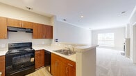 Located at 9721 Summit Circle in Upper Marlboro, MD, this one-bedroom, one-bathroom single-floor home offers a well-designed layout with a warm, neutral palette throughout. The combined kitchen and living room serves as the heart of the home, featuring plush carpeting, crown molding, and a classic fireplace with a white mantel and sleek black surround — a standout centerpiece for the space. Natural light filters in through multiple windows, providing views of the surrounding greenery. The kitchen is thoughtfully separated by a half-wall pass-through, featuring warm wood cabinetry, a skylight, and stainless steel appliances, creating an efficient and functional cooking area. The bedroom offers a comfortable and well-proportioned retreat, with soft carpeting, a large window overlooking the private deck and landscaped exterior, and direct access to the bathroom and in-unit laundry room. The bathroom includes a generously sized vanity with ample cabinetry. A dedicated laundry area with a full-size washer and dryer adds significant everyday convenience. The private deck looks out over a landscaped yard with mature shrubs and trees, offering a quiet outdoor escape in a residential neighborhood setting.