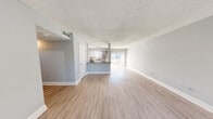 This single-floor residence offers a thoughtfully designed layout with 2 bedrooms, 2 bathrooms, and 3 closets, making efficient use of its comfortable footprint. The open-concept living and dining area is finished with light wood-tone laminate flooring and soft gray walls, creating a bright and cohesive atmosphere. A textured ceiling runs throughout the unit, adding a classic architectural detail. Large sliding glass doors and windows invite an abundance of natural light into the living area.

The kitchen is positioned at the heart of the home, defined by a peninsula counter with granite-style countertops, white cabinetry, and stainless steel appliances including a refrigerator and dishwasher. A track lighting fixture overhead ensures the space is well-lit and functional.

Both bedrooms continue the light laminate flooring and neutral gray palette. The primary bedroom features a sliding-door closet and natural light streaming through window blinds. The second bedroom includes a ceiling fan and a closet, offering practical comfort. Each bathroom is well-appointed, with one featuring a tiled glass-enclosed walk-in shower with gray subway-style tile. A hallway connects the private areas of the residence, and ample closet storage is distributed throughout the unit.