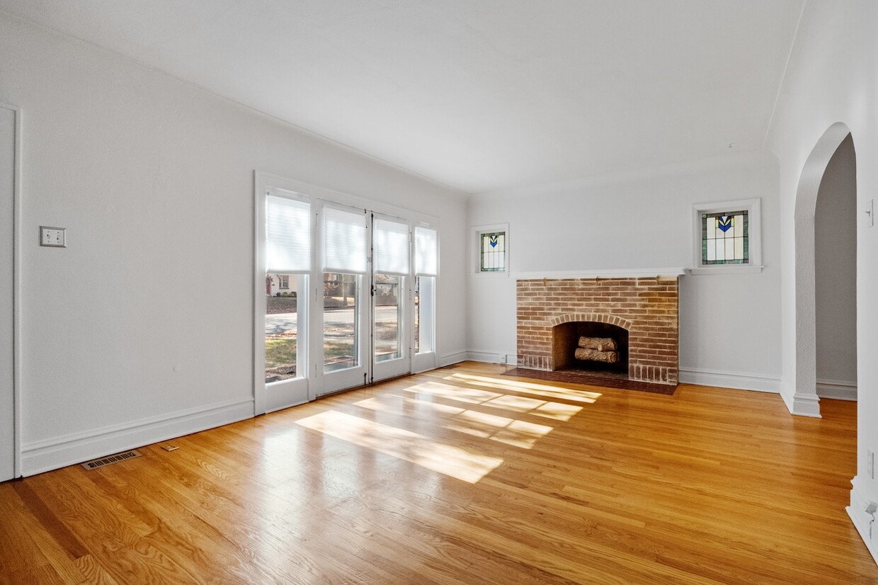 South-facing living room with stained glass windows, hardwood floors, French doors to patio - 7737 Delmar Blvd