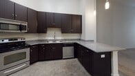Located at 735 Coleman Blvd in Mount Pleasant, South Carolina, Unit 107 is a single-floor residence that blends contemporary design with functional living. Throughout the unit, polished concrete floors provide a sleek, low-maintenance foundation that ties each space together cohesively.

The kitchen is a standout feature, showcasing rich dark espresso cabinetry extending floor to ceiling, granite countertops with subtle speckled detailing, a stainless steel sink, and a stainless steel dishwasher. A peninsula counter offers additional workspace and opens toward the living area, which benefits from impressively tall ceilings that lend the space an open, airy feel. Natural light filters in through windows fitted with horizontal blinds, and a ceiling fan adds comfort overhead.

The bedroom is generously proportioned with the same soaring ceiling height, creating a spacious and tranquil retreat. An adjacent walk-in closet provides ample storage with wire shelving and hanging rods across multiple walls.

The bathroom is cleanly designed, featuring a dark vanity with granite countertop and a single undermount sink, complemented by brushed nickel fixtures. A full tub-shower combo with tiled surround completes the space. The overall aesthetic throughout the unit is modern and neutral, offering a clean canvas well-suited to a variety of interior styles.