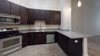 Located at 735 Coleman Blvd in Mount Pleasant, South Carolina, Unit 107 is a single-floor residence that blends contemporary design with functional living. Throughout the unit, polished concrete floors provide a sleek, low-maintenance foundation that ties each space together cohesively.

The kitchen is a standout feature, showcasing rich dark espresso cabinetry extending floor to ceiling, granite countertops with subtle speckled detailing, a stainless steel sink, and a stainless steel dishwasher. A peninsula counter offers additional workspace and opens toward the living area, which benefits from impressively tall ceilings that lend the space an open, airy feel. Natural light filters in through windows fitted with horizontal blinds, and a ceiling fan adds comfort overhead.

The bedroom is generously proportioned with the same soaring ceiling height, creating a spacious and tranquil retreat. An adjacent walk-in closet provides ample storage with wire shelving and hanging rods across multiple walls.

The bathroom is cleanly designed, featuring a dark vanity with granite countertop and a single undermount sink, complemented by brushed nickel fixtures. A full tub-shower combo with tiled surround completes the space. The overall aesthetic throughout the unit is modern and neutral, offering a clean canvas well-suited to a variety of interior styles.