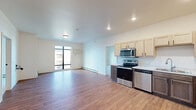 This thoughtfully designed 2-bedroom, 2-bathroom single-floor unit offers a functional and modern living experience. The open-concept layout connects the kitchen and living room, creating a bright and airy communal space. Large floor-to-ceiling windows allow abundant natural light to fill the living area, which features warm wood-look flooring throughout. The kitchen is equipped with a full suite of stainless steel appliances, including a refrigerator, electric range, microwave, and dishwasher. Light wood upper cabinetry is paired with contrasting darker lower cabinets, complemented by a clean white countertop.

Both bedrooms are carpeted for comfort, with the generously sized primary bedroom featuring a walk-in closet outfitted with wire shelving systems for ample storage. Each bedroom offers access to natural light through well-placed windows with exterior views. The two bathrooms are finished with wood-look flooring, dark-cabinetry vanities, white countertops, and walk-in shower enclosures. A dedicated in-unit laundry room houses a full-size top-load washer and dryer, adding everyday convenience. The unit's clean, neutral palette and modern finishes create a cohesive and move-in-ready living environment.