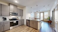 This thoughtfully designed one-bedroom, one-bathroom residence offers a cohesive open-concept layout that maximizes its efficient footprint. Light wood-style flooring flows throughout, unifying the living, dining, and kitchen areas into a seamless, functional space.

The kitchen is a standout feature, showcasing grey flat-front cabinetry, granite countertops, a herringbone tile backsplash, and a full suite of stainless steel appliances including a refrigerator, range, microwave, and dishwasher. A peninsula with pendant lighting and bar seating provides both additional prep space and a casual dining area.

The living room is bright and inviting, benefiting from abundant natural light through large windows and a glass balcony door that opens to an outdoor space with exterior views. The bedroom offers a serene retreat with a bold accent wall, wide windows, wood-look flooring, and ample room for full-sized furnishings.

The bathroom is finished with the same granite countertop seen throughout, a grey vanity with undermount sink, a large mirror, and a shower-tub combination. Clean neutral tones and consistent finishes across every room give the space a modern, polished, and cohesive aesthetic.
