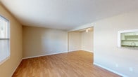 This single-floor, two-bedroom, two-bathroom unit offers a practical and comfortable layout designed to maximize livable space. The open living and dining areas are connected seamlessly, with warm wood-look flooring running consistently throughout the main spaces. A ceiling fan overhead in the dining area adds functionality, while a pass-through window connects this area to the kitchen, enhancing the sense of openness.

The kitchen is efficiently designed with white cabinetry, granite-style countertops, and a black electric range with an overhead exhaust hood, providing ample prep and storage space in a clean, galley-style arrangement.

Both bedrooms feature the same warm wood-look flooring, neutral beige walls, and windows that allow natural light and outdoor views of greenery. Closet space is well-appointed, including a walk-in closet with wire shelving and hanging rods, as well as a standard bifold-door closet in the second bedroom.

The two bathrooms are cleanly finished in white, each offering a full tub-shower combination with tiled surrounds, a vanity with sink, and adequate overhead ventilation. Textured ceilings and white baseboards are consistent throughout, giving the unit a cohesive, neutral aesthetic well-suited for a variety of furnishing styles.
