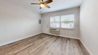 Located at 4949 W Century Blvd in Inglewood, California, this efficiently designed single-floor unit offers a thoughtful layout comprising a living room, kitchen, and bathroom. Throughout the space, warm wood-look plank flooring creates a cohesive and contemporary feel, complemented by crisp white walls and clean white baseboards.

The living room is bright and open, featuring a ceiling fan with light fixture, a wall-mounted PTAC heating and cooling unit, and windows fitted with white horizontal blinds that invite natural light while maintaining privacy. A recessed electrical panel is neatly integrated into the wall, keeping the space streamlined.

The kitchen connects to the living area through an arched passage and is equipped with stainless steel appliances, including a gas range, over-the-range microwave, and a full-size refrigerator. White cabinetry and a window above the counter further enhance the clean, functional aesthetic.

The bathroom is accessed through a hallway and features a glass-enclosed walk-in shower with white tile surround, a toilet, a large wall mirror, and continued wood-look flooring. The recessed lighting and frameless glass shower door give the bathroom a polished, modern finish.

Overall, the unit presents a clean, move-in ready design with consistent modern finishes throughout, well-suited for efficient urban living in the heart of Inglewood.
