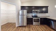 Located at 17 Hawthorne Gate in Dayton, Ohio, this single-floor home offers a well-designed layout with a consistent, neutral color palette and a mix of wood-look vinyl and plush carpet flooring throughout. The kitchen is outfitted with rich, dark cabinetry, granite-look countertops, and a full suite of stainless steel appliances including a refrigerator, range, and built-in microwave. A pantry closet is conveniently accessible from the kitchen. The bedrooms feature warm, neutral carpeting, ceiling fans with light fixtures, and windows with blinds that allow for ample natural light. The primary bedroom includes a spacious walk-in closet with built-in wire shelving and hanging rods for generous storage. Two bathrooms serve the home: one features a dual-sink dark vanity with a tub/shower combination and wood-look vinyl flooring, while the second offers a single-sink vanity, a shower, and a bright vanity light fixture. The attached garage is equipped with an automatic opener, a paneled door with windows, and a concrete floor, offering practical vehicle and storage space. The overall layout, as seen in the dollhouse view, flows openly and efficiently across the single level.