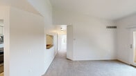 The Brussels floor plan is a single-level unit offering three bedrooms and one bathroom across a thoughtfully designed layout. The living room serves as the heart of the home, highlighted by soaring vaulted ceilings that lend an open, airy feel. A wood-mantled fireplace with tile surround anchors the space, while a sliding glass door opens to a private balcony with outdoor views. A pass-through window connects the living area to the kitchen, enhancing the sense of openness.

The galley-style kitchen is efficiently designed with white cabinetry, dark granite-style countertops, tile flooring, and stainless steel appliances including a refrigerator, range, and dishwasher. A dedicated dining area with a pendant light fixture flows naturally from the kitchen.

The bedrooms are carpeted and well-lit by natural light from large windows. The primary bedroom includes access to the full bathroom and a spacious walk-in closet with wire shelving. The bathroom features a tub/shower combo, tile flooring, and granite-style countertops. Neutral tones and plush carpeting throughout create a clean, cohesive ambiance.