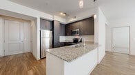 Located at 1100 E Bell Rd in Phoenix, AZ, this well-designed single-floor residence offers three bedrooms, two bathrooms, and a thoughtful layout that maximizes functionality and comfort. The open-concept kitchen and living area serves as the heart of the home, featuring a large granite-topped island with a stainless steel sink, dark espresso cabinetry extending to the ceiling, and a full suite of stainless steel appliances including a refrigerator, range, microwave, and dishwasher. Pendant lighting and track lighting illuminate the kitchen, while wood-style plank flooring flows seamlessly into the spacious living room, which is brightened by multiple windows with blinds and anchored by a ceiling fan. The primary bedroom offers generous proportions, wood-style flooring, dual windows, and a ceiling fan, complemented by a walk-in closet with built-in shelving and hanging rods. The two additional bedrooms feature plush carpeting and natural light. Both bathrooms are finished with granite vanity countertops, dark cabinetry, and wood-style flooring; the full bath includes a tub-shower combination. Two hallways and three closets provide ample storage throughout the residence, completing this clean, modern living space.
