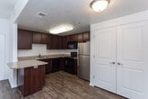 Located at 14532 S Triathlon Way in Draper, Utah, this single-floor unit offers a well-organized and functional layout designed for comfortable everyday living. The main living area features wood-look laminate flooring and a ceiling fan light fixture, with sliding glass doors that open to a private balcony, allowing natural light to fill the space and providing views of the surrounding area.

The kitchen is equipped with dark espresso-toned cabinetry, granite-style countertops, and stainless steel appliances including a refrigerator, alongside a black electric range and microwave. A peninsula counter serves as a natural divider between the kitchen and living area. Conveniently adjacent to the kitchen, an in-unit laundry closet houses a full-size washer and dryer.

The bedrooms are finished with plush neutral carpeting and feature windows that bring in natural light. The layout provides a clear sense of separation between the living and sleeping areas. The bathroom is well-appointed with warm tile flooring set in a diagonal pattern, rich wood vanity cabinetry topped with a granite-style countertop and single-basin sink, a large mirror, and a full tub-shower combination. The overall palette throughout is light and neutral, creating a clean, move-in-ready atmosphere.