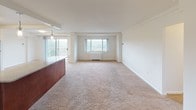 This single-floor residence offers a thoughtfully designed layout that balances open communal spaces with comfortable private areas. The expansive living and dining area is bathed in natural light from multiple windows, including a sliding glass door that opens to a private balcony overlooking a lush outdoor setting. Plush wall-to-wall carpeting runs throughout the living spaces and bedrooms, contributing to a warm and inviting atmosphere.

The kitchen is outfitted with rich dark wood cabinetry, granite countertops, and a full suite of stainless steel appliances including a gas range, built-in microwave, dishwasher, and refrigerator. A light blue tile backsplash adds a subtle decorative accent, and tile flooring provides a clean, durable surface underfoot. A breakfast bar with a granite overhang connects the kitchen to the living area.

The bedrooms feature soft carpeting and generous proportions, with at least one room offering a spacious walk-in closet with built-in shelving. Two bathrooms serve the residence: one featuring a soaking tub with floor-to-ceiling dark tile surround and granite vanity, and another with a tiled walk-in shower and matching wood vanity with granite countertop.
