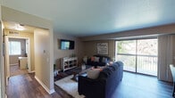 Located at 5220 Hedgewood Dr in Midland, Michigan, this well-appointed single-floor residence offers a thoughtfully designed layout with warm, neutral tones and wood-look flooring throughout the main living areas. The living room is a welcoming focal point, featuring a large sliding glass door that opens to a private balcony with outdoor views, filling the space with natural light. The room comfortably accommodates a full seating arrangement and a wall-mounted television. Adjacent to the living area is a dedicated dining space with a ceiling fan overhead, providing an intimate setting for meals. The galley-style kitchen is efficiently organized with dark espresso cabinetry, granite-look countertops, and black appliances, including a refrigerator, range, microwave, and dishwasher, along with ample storage and a double sink. The primary bedroom offers plush carpeting, a ceiling fan, and a window with outdoor views, while a second bedroom mirrors similar features and comfort. The primary bathroom is well-equipped with a double-sink vanity, dark wood cabinetry, granite-look countertops, and stylish lighting. This residence combines functional design with a cozy, inviting ambiance throughout.