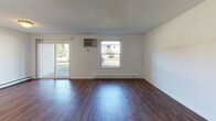 Located in Somerset, MA, this single-floor unit offers a functional and well-organized layout designed for comfortable everyday living. The open living area is finished with rich, dark hardwood-style flooring and features multiple windows, including a sliding glass door, that flood the space with natural light and provide views of the surrounding greenery and community grounds. Baseboard heating and a wall-mounted air conditioning unit ensure year-round climate control throughout the living spaces.

The kitchen is thoughtfully equipped with white shaker-style cabinetry, granite-look countertops, and a full suite of stainless steel appliances, including a refrigerator, electric range with overhead exhaust hood, dishwasher, and a single-basin sink — offering both practicality and a clean, modern aesthetic.

The carpeted bedroom areas provide a comfortable retreat, with one room featuring dual closet access and another offering a generously sized walk-in closet with built-in shelving. The full bathroom is finished in crisp white tones, featuring a single-sink vanity with white cabinetry, a full-size tub and shower combination, and hardwood-style flooring. Throughout the unit, the clean white walls and neutral palette create a bright, move-in-ready environment.