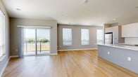 Located on State Line Road in Kansas City, KS, this 2-bedroom, 2-bathroom residence offers a well-designed, single-floor layout with a clean, modern aesthetic throughout. The open-concept living and kitchen area serves as the heart of the home, featuring light hardwood flooring that extends seamlessly across the space. Multiple windows fitted with blinds flood the room with natural light, while a sliding glass door opens onto a private balcony with outdoor views. The kitchen is equipped with stainless steel appliances, including a refrigerator, range, and microwave, complemented by flat-front cabinetry in a two-tone white and gray finish, a subway tile backsplash, and a large central island with a white countertop and integrated sink. Both bedrooms are carpeted and receive ample natural light through generously sized windows. The primary bedroom includes a walk-in closet with wire shelving for organized storage. The bathrooms feature modern gray vanities, large mirrors, and a tub-shower combination. A dedicated laundry area with an in-unit washer provides added convenience. Neutral gray wall tones and consistent finishes create a cohesive, contemporary ambiance throughout the entire residence.