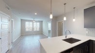 Located at 905 S Harwood St in Dallas, TX, this single-floor residence presents a clean, modern aesthetic with an open and well-connected layout. The kitchen serves as a central hub, featuring dark flat-front cabinetry, a light gray subway tile backsplash, stainless steel appliances including a gas range, microwave, and French door refrigerator, and a expansive white quartz island with an undermount sink. Pendant lighting illuminates the island, which flows seamlessly into the living area. The living space is finished with light wood-look flooring, recessed lighting, a ceiling fan, and windows fitted with white plantation shutters that allow generous natural light and views of the surrounding cityscape. The bedrooms are carpeted and each feature ceiling fans and windows with blinds, offering comfortable, well-lit retreats. A walk-in closet with dual hanging rods provides ample storage. The bathrooms are elegantly appointed with marble-style tile surrounds, a glass-enclosed shower, a soaking tub, dark vanity cabinetry, white quartz countertops, and wide-format mirrors with accent lighting. Light wood-look flooring carries through the wet areas, tying the design together cohesively.