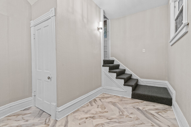 Shared hallway space, stairs go to upper unit, door leads to basement/laundry. - 2925 Holmes St