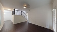 This two-story residence showcases a thoughtful layout across both levels, combining modern finishes with functional design. The main level is anchored by rich, dark hardwood flooring that flows throughout the living and dining areas. A standout architectural feature is the staircase, framed by elegant dark iron balusters and a classic handrail, accented by crown molding and a ceiling light fixture overhead. The living area is bright and open, with a glass-paned door and wide windows fitted with horizontal blinds allowing natural light to filter in.

The kitchen is well-appointed with white shaker-style cabinetry extending to the ceiling, granite countertops, a subway tile backsplash, and a full suite of stainless steel appliances including a range, microwave, dishwasher, and refrigerator. A peninsula with a granite overhang provides additional prep and seating space. A window above the sink adds natural light to the workspace.

Upstairs, the bedrooms feature plush carpeting, ceiling fans, and windows that bring in natural light. The bathrooms are finished in a clean, neutral palette — one offering a soaking tub with tiled surround and showerhead, and another featuring a dual-sink vanity with granite countertops, shaker cabinetry, and a well-lit mirror.