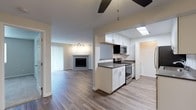 This single-floor residence offers a thoughtfully designed open-concept layout that seamlessly connects the living, dining, and kitchen areas. The living room is a welcoming space anchored by a classic fireplace, warm wood-look flooring, and a ceiling fan, with sliding glass doors that invite natural light and provide access to an outdoor area with greenery views. A pass-through window connects the living space to the kitchen, enhancing the open feel.

The kitchen is efficiently designed in a galley style, featuring crisp white cabinetry with modern hardware, dark countertops, and a full suite of stainless steel appliances including a refrigerator, dishwasher, electric range, and over-the-range microwave. A skylight overhead adds an extra touch of brightness to the cooking space.

Adjacent to the kitchen is a versatile dining or bonus area, also fitted with a ceiling fan and continued wood-look flooring. The bedroom offers a calm retreat with plush carpeting, a large window framing outdoor views, and a baseboard heating system. The bathroom is clean and contemporary, featuring a soaking tub with shower, white cabinetry with dark countertops, and wood-look tile flooring. The neutral color palette and consistent finishes throughout give the entire space a cohesive, move-in-ready appeal.