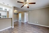 This single-story 2-bedroom, 2-bathroom home offers a practical and comfortable layout across a well-utilized floor plan. Rich, dark hardwood-style flooring runs throughout the entire space, lending warmth and visual continuity from room to room. The combined dining and living area serves as the heart of the home, featuring crown molding, a ceiling fan with integrated lighting, and a textured ceiling. Natural light filters in through windows dressed with blinds, brightening the neutral taupe-toned walls. The kitchen is positioned adjacent to the living area and features granite-style countertops, providing a convenient flow for everyday living. Both bedrooms are generously proportioned, each equipped with ceiling fans and windows that bring in natural light. The spacious primary bedroom includes access to one of five closets found throughout the home, offering abundant storage. The two bathrooms are clean and functional, each featuring a tub-shower combination with built-in shelving niches and hardwood-style flooring. A dedicated laundry area adds everyday convenience. A connecting hallway ties the layout together efficiently, making this home practical and easy to navigate.