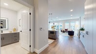 This elegantly designed single-floor residence offers a seamless open-concept layout that connects the kitchen, dining, and living areas into one cohesive, light-filled space. Wide-plank hardwood flooring flows throughout the main living areas, anchoring the contemporary aesthetic.

The chef's kitchen is a standout feature, equipped with dark gray cabinetry, crisp white quartz countertops, a large center island with a black matte faucet, and premium stainless steel appliances including a professional-grade gas range, a wall-mounted pot filler, a built-in microwave, and a wine refrigerator. Statement pendant lighting adds visual interest above the island.

The living area is bathed in natural light through floor-to-ceiling windows that frame expansive urban skyline views, creating a bright and inviting atmosphere. Recessed lighting complements the open, airy feel throughout.

The bedroom is generously proportioned with plush carpeting, large windows with city views, and a stylish sliding barn door leading to a walk-in closet. A hallway connects to a well-appointed bathroom featuring gray cabinetry, white quartz countertops, light tile flooring, and clean, minimalist fixtures. A powder room with similar finishes provides additional convenience. The overall ambiance is polished, modern, and ideally suited for urban living.