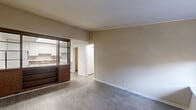 Located at 5421 Covington Hwy in Decatur, GA, this single-floor, one-bedroom, one-bathroom unit offers a practical and efficient layout across a compact footprint. The living room features light-toned hardwood-style flooring and neutral beige walls, creating a clean and bright atmosphere. A sliding partition with warm wood framing and shelving separates the living area from the kitchen, adding a distinctive design element. The kitchen is equipped with white cabinetry, brown laminate countertops, a stainless steel sink, and a full-size refrigerator, all finished with matching hardwood-style floors and a skylight-style overhead fixture. The bedroom is carpeted in a warm tan tone, fitted with a ceiling fan, and includes a window that allows for natural light and exterior views. The bathroom offers a combined tub and shower, a vanity with marble-patterned countertop, and light hardwood-style flooring. A dedicated laundry and utility area houses the water heater and provides additional functional space. A hallway connects the rooms, and a closet offers supplementary storage. Crown molding is present throughout, adding a refined finishing touch to each room.