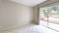 Located at 317 Craddock Ave in San Marcos, TX, this two-story, 2-bedroom, 2-bathroom home is thoughtfully laid out across two floors. The ground floor features a combined kitchen and dining area with a pass-through bar counter, dark cabinetry with an overhead range hood, light tile flooring, and a window that brings in natural light. The living and dining area opens to a private patio through sliding glass doors, offering pleasant outdoor views of a tree-lined, fenced backyard. A second room on the lower level, also finished in light tile, provides flexible use as an additional bedroom or living space. The upper floor is home to the generously sized primary bedroom, featuring warm hardwood flooring, a ceiling fan with light fixture, and a large window framing greenery outside. A second bedroom upstairs also offers hardwood floors, a ceiling fan, and a bright window. Both bathrooms are finished in light tile and feature gray cabinetry with speckled countertops and mirrored medicine cabinets; one includes a full tub-shower combination. A wood-railed staircase connects the two floors, completing this functional and well-appointed home.