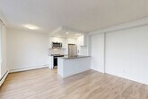 Located on the 16th floor at 151 Keith Rd E in North Vancouver, this 2-bedroom, 1-bathroom residence offers an efficiently designed open-concept layout with light hardwood flooring throughout. The combined kitchen and living area serves as the heart of the home, featuring a peninsula with dark countertops, white shaker cabinetry, a herringbone tile backsplash, and a full suite of stainless steel appliances including a range, over-the-range microwave, refrigerator, and dishwasher. Floor-to-ceiling sliding glass doors connect the living space to a private balcony, framing sweeping views of Burrard Inlet and the Vancouver city skyline. Both bedrooms are well-proportioned and bright, with large windows capturing the same remarkable waterfront and cityscape views. The primary bedroom includes a mirrored sliding-door closet, while additional closet storage is provided throughout the unit. A clean, neutral hallway connects the bedrooms to the full bathroom, which is finished with white subway tile walls, slate-grey floor tiles, and a vanity with a white countertop. Three closets provide ample storage across the unit. The overall aesthetic is bright, modern, and well-maintained, making for a functional and visually appealing home in a prime North Vancouver location.