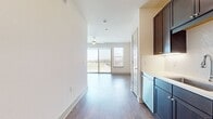 This contemporary 470 square foot one-bedroom apartment in Central Square at Frisco offers a thoughtfully designed living space. The open-concept layout seamlessly integrates the kitchen, living, and dining areas, creating an airy and spacious feel. The kitchen boasts dark wood cabinetry, stainless steel appliances, and a subway tile backsplash, providing both style and functionality. Warm wood-look flooring flows throughout, adding warmth and continuity to the space.

The bathroom features a large vanity with ample storage, a spacious bathtub, and modern tile work. A walk-in closet offers generous storage space. The living area is bright and inviting, with recessed lighting and a modern ceiling fan. Large windows, including a sliding glass door, flood the space with natural light and provide panoramic city views. The apartment's neutral color palette creates a blank canvas for personalization.

Additional amenities include in-unit laundry facilities and smart home features like digital locks. This efficiently designed apartment maximizes every square foot, offering comfortable urban living in a prime Frisco location.