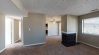 Located on Patchen in Lexington, Kentucky, this single-floor home offers a functional and comfortable layout throughout. The main living area is highlighted by a striking double-sided fireplace with a dark surround, serving as an architectural focal point between the living and dining spaces. Plush wall-to-wall carpeting runs throughout the living areas and bedrooms, while a ceiling fan overhead adds both style and practicality. Neutral taupe walls and textured ceilings create a consistent, understated aesthetic throughout the home.

The galley-style kitchen is well-appointed with bold black cabinetry, white countertops, and stainless steel appliances including a refrigerator, electric range, and dishwasher. Stone-look tile flooring grounds the kitchen and extends into the bathroom, providing a durable and easy-to-maintain surface.

The bedrooms are generously sized, each featuring soft carpeting, large windows that invite natural light, and ample wall space. The bathroom is cleanly finished with a wide vanity, large mirror, a tub/shower combination, and matching tile flooring.

Natural light flows into multiple rooms through blinds-fitted windows, offering views of the surrounding greenery. The home's single-floor layout ensures easy accessibility and a seamless flow between spaces.
