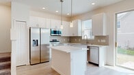 Located in Davenport, Florida, this well-designed two-story home showcases a bright, contemporary aesthetic with light wood-style flooring and crisp white walls carried consistently throughout. The open main living area is bathed in natural light from large sliding glass doors, complemented by recessed lighting and a ceiling fan, creating an airy and welcoming atmosphere. The kitchen is a standout feature, boasting white shaker-style cabinetry, a subway tile backsplash, sleek quartz countertops, a central island with pendant lighting, and a full suite of stainless steel appliances including a refrigerator with ice maker, range, microwave, and dishwasher. A staircase leads to the upper level, where the primary bedroom impresses with a tray ceiling, ceiling fan, and generous proportions. It is accompanied by a spacious walk-in closet outfitted with wire shelving systems for organized storage, and a bathroom featuring a soaking tub with brushed gold fixtures. Additional bedrooms are well-sized, each with light-filled windows and ceiling fans. Throughout the home, clean lines, neutral tones, and thoughtful details combine to create a move-in ready residence that feels both modern and comfortable.