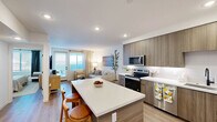 Located in Murrieta, CA, this single-floor residence offers a thoughtfully designed layout encompassing a kitchen, living room, bedroom, bathroom, and closet. Light wood-tone flooring runs consistently throughout the space, creating a cohesive and warm aesthetic.

The kitchen is outfitted with flat-front cabinetry in a warm wood grain finish, a stainless steel French door refrigerator, under-cabinet lighting, a matte black faucet, and white quartz countertops — delivering a clean, contemporary look. The open flow between the kitchen and living area enhances the sense of space.

The living room benefits from natural light through a glass-panel exterior door flanked by window blinds and linen drapes, creating a bright and inviting atmosphere. The space opens seamlessly to the kitchen, making it ideal for everyday living.

The bedroom is a comfortable retreat with a ceiling fan with light, a window with blinds and drapes, and ample room for a full furniture arrangement. White paneled doors with matte black hardware lead to the closet and other areas, maintaining a consistent modern design language.

The bathroom features a soaking tub with a shower combo, a curved curtain rod, built-in open shelving with woven storage baskets, and a clean white tile surround. Throughout the space, white walls and recessed lighting contribute to a bright, airy ambiance.