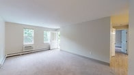Located at 112 Charles St in Mansfield, Massachusetts, this single-floor residence offers a clean, neutral aesthetic throughout. The layout, as seen in the floor plan, includes generously sized living and bedroom spaces, a well-appointed kitchen, two full bathrooms, and access to a private outdoor deck.

The living area is expansive and filled with natural light from multiple windows that frame views of surrounding greenery. Plush wall-to-wall carpeting and soft neutral wall tones create a calm, welcoming atmosphere. A front entry door provides convenient access, and baseboard heating ensures year-round comfort.

The kitchen is outfitted with white cabinetry, stainless steel appliances including a range, microwave, and dishwasher, as well as light wood-look tile flooring that adds warmth and easy maintenance.

The bedrooms are spacious, carpeted, and feature ample natural light. One bedroom includes access to a walk-in closet and connects to a hallway leading to additional rooms.

Two full bathrooms serve the residence — one featuring a soaking tub and shower combination, the other a standalone shower stall. Both bathrooms are finished with light wood-look tile flooring and white fixtures, lending a clean, modern feel throughout.